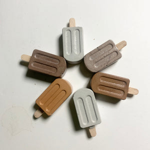 Set of six popsicle-shaped magnets in brown, gray, and beige on a white background