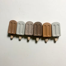 Row of brown and beige concrete popsicle magnets on a white background